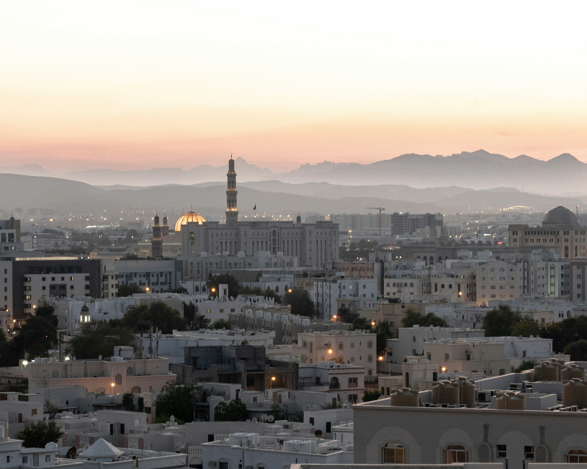 Muscat skyline at dusk with Sultan Qaboos Grand Mosque and the Hajar mountains